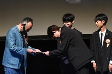 色紙をプレゼントされる足立紳（左）。