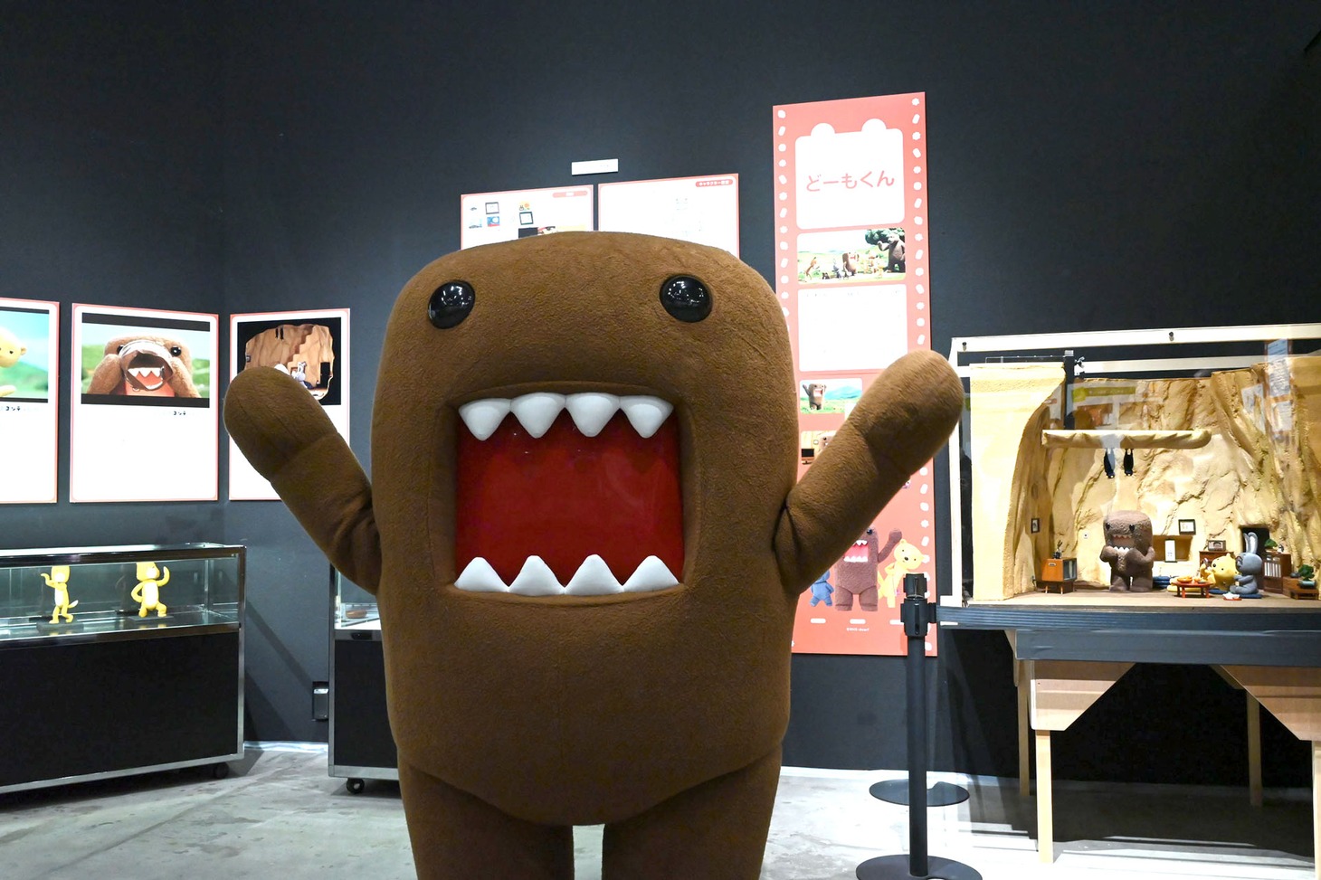 「どーもくん」展示コーナーを紹介するどーもくん。