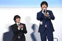 黒澤武蔵のアクリルスタンド、「りお（内田理央）」と書かれた紙をアピールする田中圭（右）。左は田中を見守る林遣都。