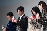 入場者プレゼントのカードを開封する登壇者たち。左から飯塚健、戸塚純貴、西野七瀬、中条あやみ。