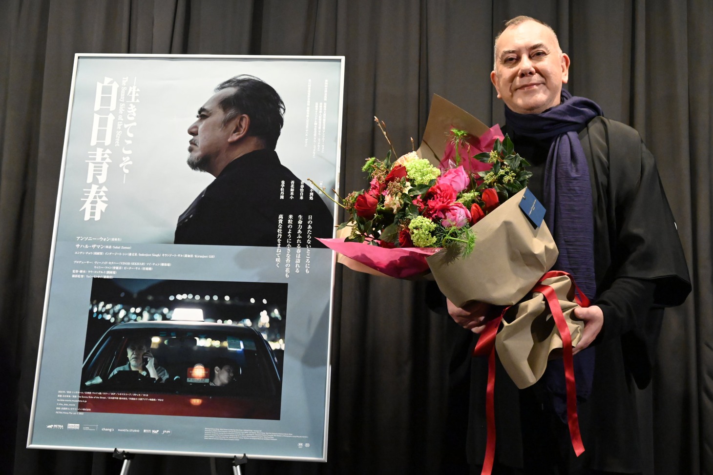 劇場スタッフから受け取った花束を手にするアンソニー・ウォン。