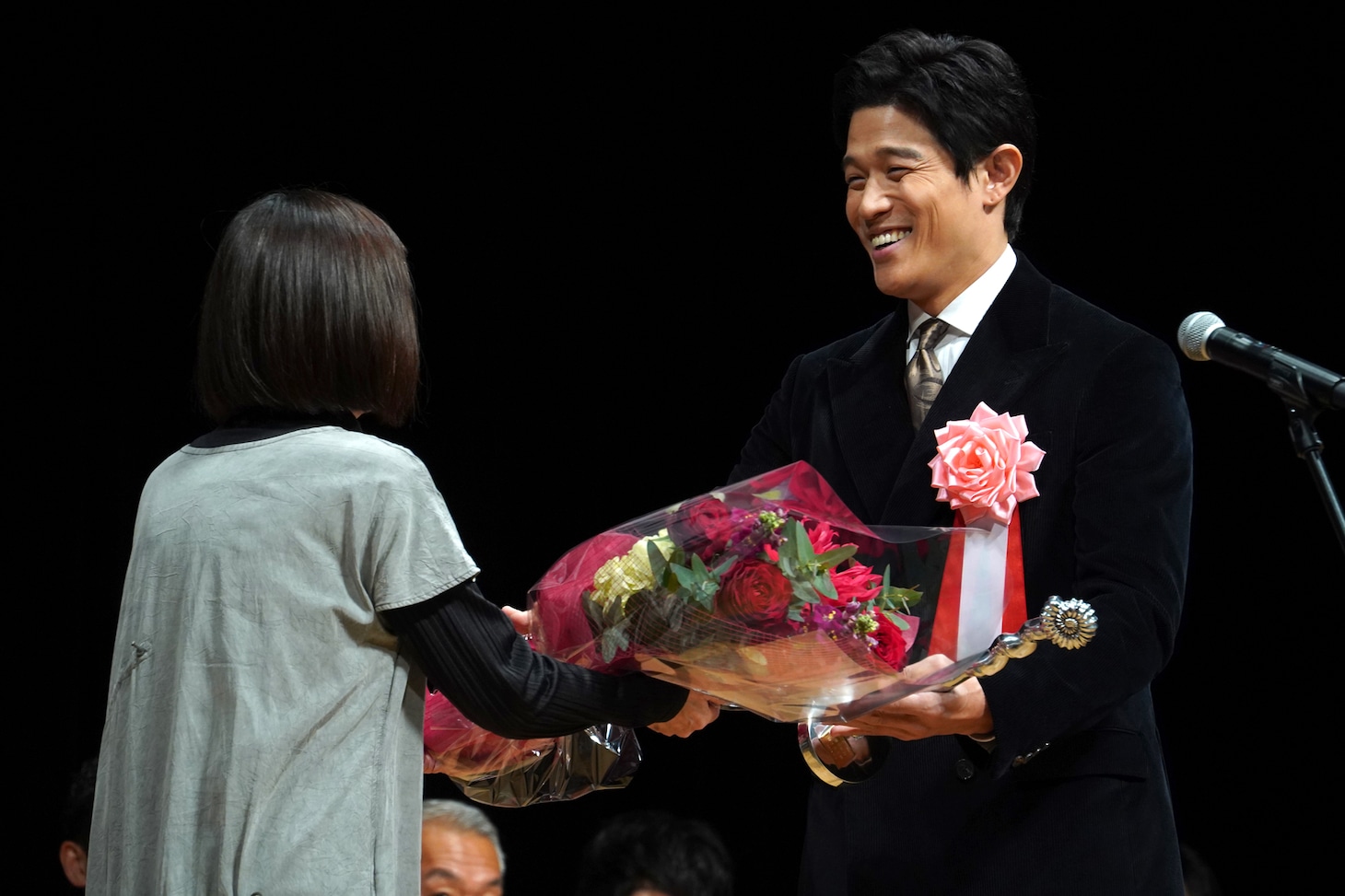 映画プロデューサーの三沢和子から花束を受け取った鈴木亮平（右）。