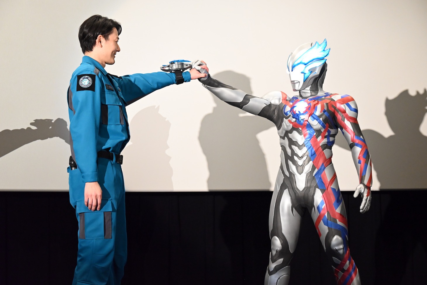 最終回で手をつなぐシーンを再現する蕨野友也とウルトラマンブレーザー。