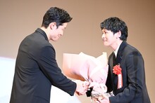 眞栄田郷敦（右）に花束を手渡す鈴木亮平（左）。