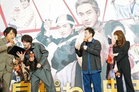 司会の本多力（左）の台本をのぞき込み、進行をサポートする登壇者たち。