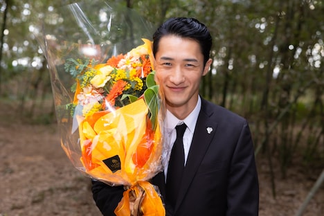 花束を抱えてほほえむ岩本照。