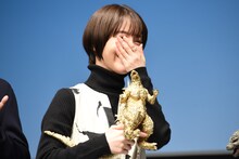 「ゴジラ像をもう少し下に持ってください」と報道陣に頼まれ、恥ずかしそうに笑う浜辺美波。