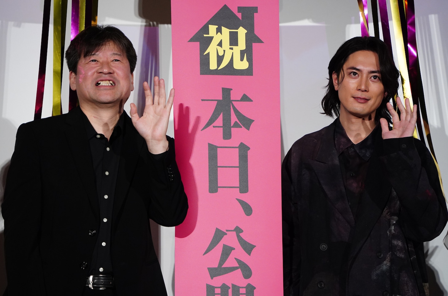 手を振る間宮祥太朗（右）と佐藤二朗（左）。