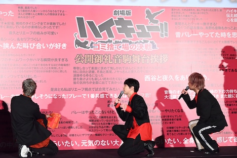 SNSの投稿文が印刷されたボードを見る登壇者たち。