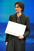 “トモダチ”と記したフリップを抱える柳俊太郎。