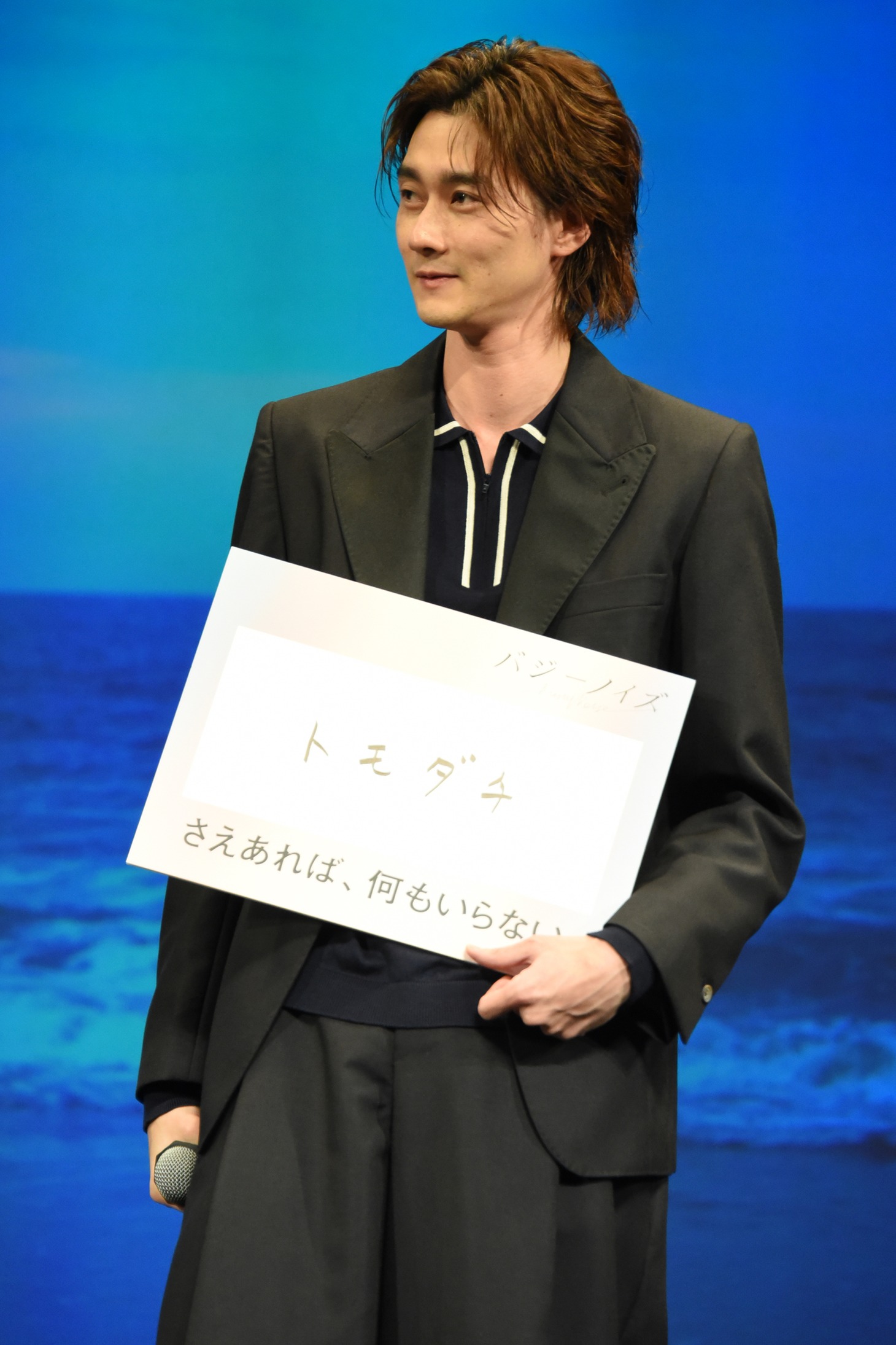 “トモダチ”と記したフリップを抱える柳俊太郎。