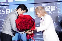 鈴木亮平（左）に花束を手渡す小室哲哉（右）。