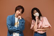 左から綿貫大介、明日菜子。ポーズは、朝ドラ「虎に翼」の主人公・猪爪寅子の口癖である「はて？」をイメージしたもの。