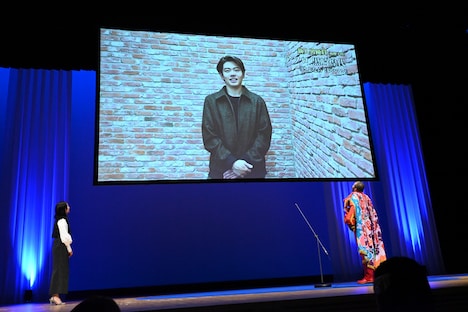 黒崎煌代からのビデオメッセージを見つめるアフロ(右)。