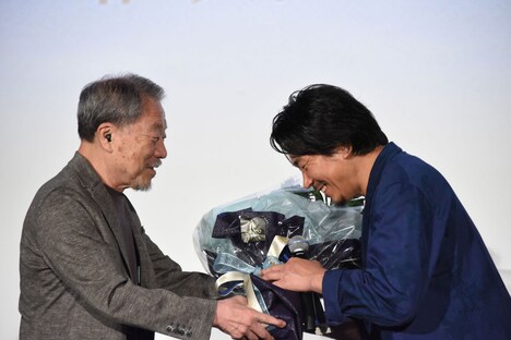 かわぐちかいじ（左）から花束を受け取るヤン・イクチュン（右）。