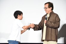 山田くん（左）と握手するジャッキー・チェン（右）。