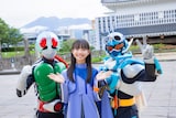桜島をバックに仮面ライダー1号（左）と仮面ライダーガッチャード（右）と記念撮影をした松本麗世（中央）。