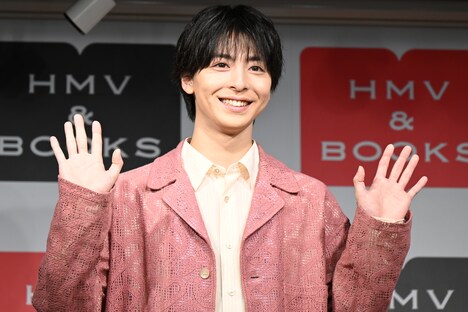 手を振るポーズを求められ笑顔を見せる高杉真宙。