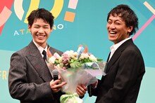 子犬のような笑みを浮かべる木村柾哉（左）と、花束を贈呈する横堀光範（右）