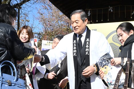 「黒豆ふるまいセット」を参拝客に手渡す松平健（中央）