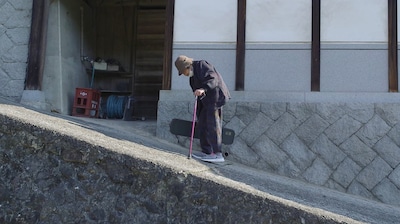 「104歳、哲代さんのひとり暮らし」場面写真。哲代さんは転ばないように坂道を後ろ向きで下りる