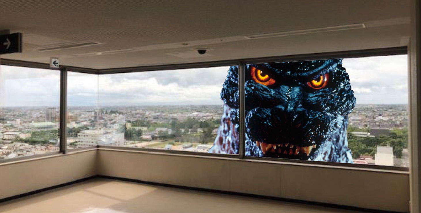 佐賀県庁の窓の外から建物の中をのぞくゴジラ