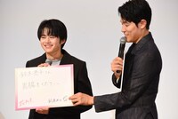 鈴鹿央士（左）が描いたカラスのイラストを指して「双眼鏡で見てください！」とアピールする鈴木亮平（右）