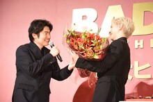 ⻄川達郎（左）から、メンバーカラーの赤で彩られた花束を受け取った豆原一成（右）