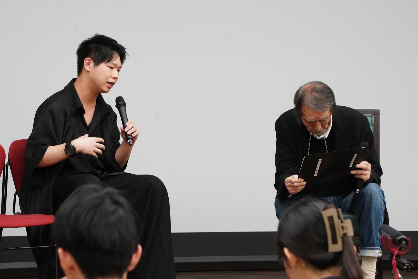 質問者の学生（左）が持ち込んだ舞台装置の設計ビジュアルを熱心に見る山崎努（右）