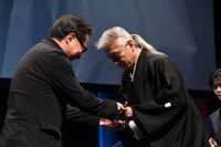 トロフィーを受け取る本山力（右）