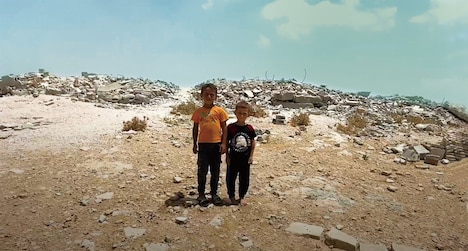 「壁の外側と内側」より、マサーフェル・ヤッタのスファイフォガ村で学校が破壊された丘を背景に立つ少年