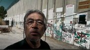 「壁の外側と内側」より、イスラエルがヨルダン川西岸との間に建設した分離壁の前でレポートする川上泰徳