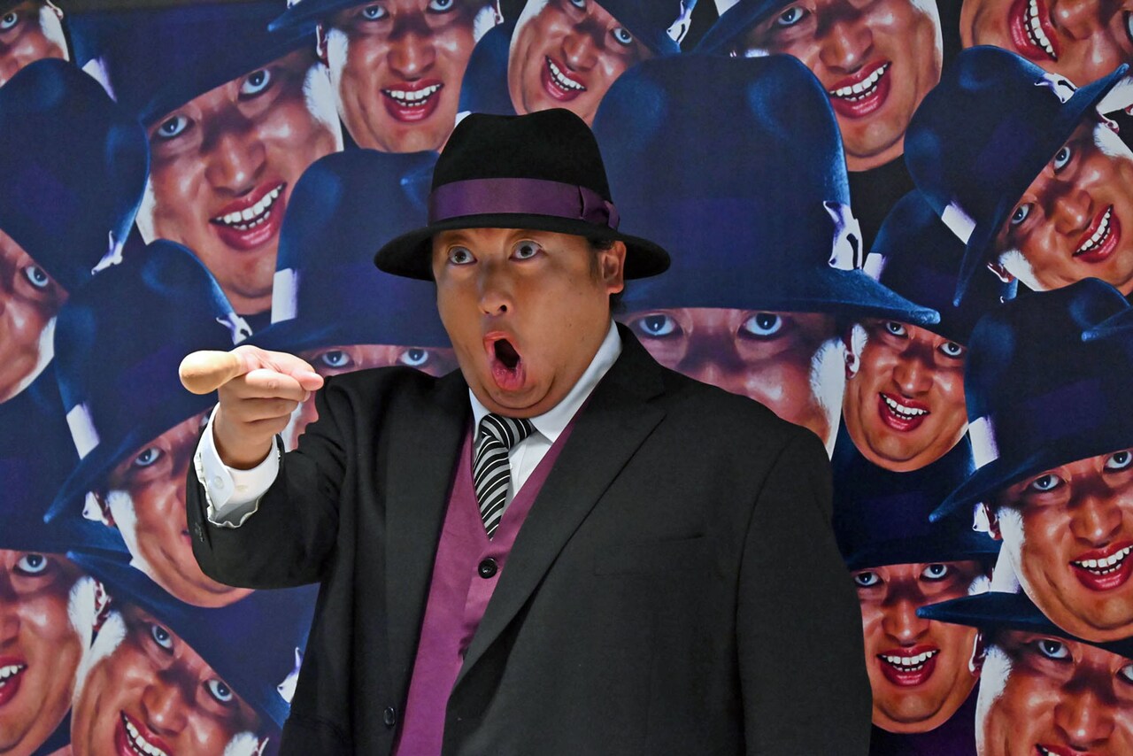 ドラマのビジュアルを背景に記念撮影するロバート秋山