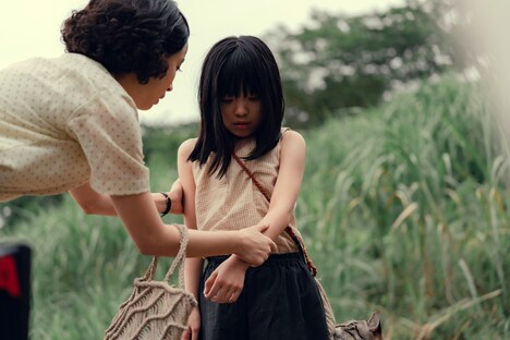 映画「遠い山なみの光」新場面写真より、万里（鈴木碧桜 / 中央）の腕に何かを見つけ、驚いた様子を見せる悦子（広瀬すず / 左）