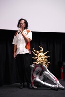 藤井亮（左）の足元に座り込むタローマン（右）