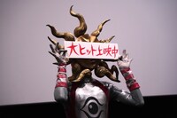 「大ヒット上映中」のパネルを顔の前で掲げるタローマン