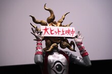 「大ヒット上映中」のパネルを顔の前で掲げるタローマン