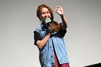 109シネマズプレミアム新宿限定の入場者特典・ギターピック風カードを見せるPeco