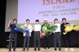 「宝島」特別上映会にて、学生たちと記念撮影するジョン・カビラ（左から2番目）、真藤順丈（中央）、大友啓史（右から2番目）