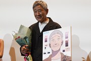 誕生日プレゼントの花束と似顔絵を手にする小林薫