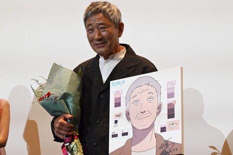 誕生日プレゼントの花束と似顔絵を手にする小林薫