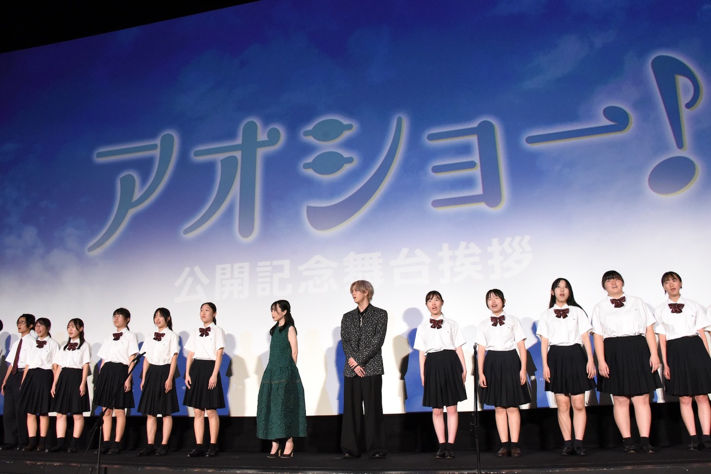 RAN（中央右）と山川ひろみ（中央左）が、東京都立小金井北高校のコーラス部18名とともに「君がみた海」を合唱する様子