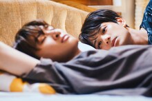 「（LOVE SONG）」場面写真。眠っているカイ（向井康二）の横顔をどこか悲しげな表情で見つめるソウタ（森崎ウィン）