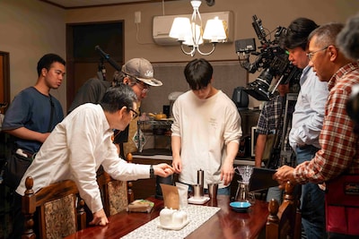 「富士山と、コーヒーと、しあわせの数式」メイキング写真。UCCコーヒーアカデミー講師の川口雅也氏から、おいしいコーヒーを淹れるための技術を伝授される豆原一成