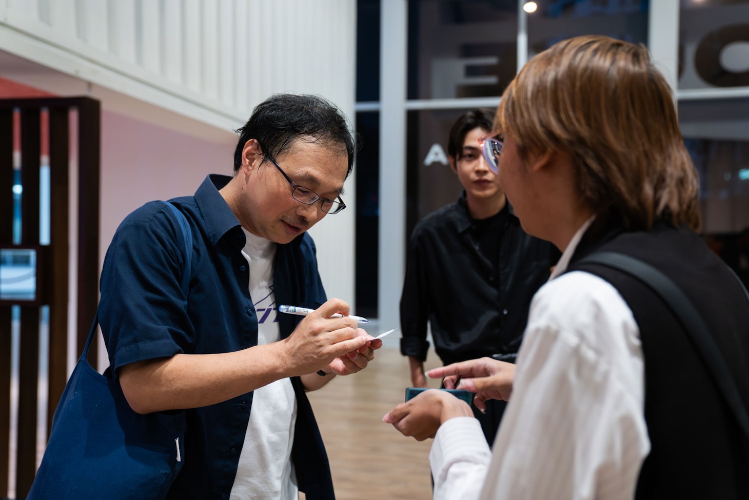 バンコク国際映画祭の「恋愛裁判」公式上映にてファンにサインする深田晃司