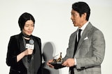 シム・ウンギョン(左)とトロフィーの重さを確かめる堤真一(右)