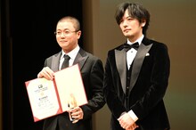 第10回ゴールドクレイン賞（金鶴賞）授賞式の様子。左からシャオ・ヤン（肖央）とプレゼンターの久保田悠来