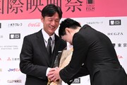 李相日（左）とがっちり握手を交わす吉沢亮（右）