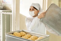 「おいしい給食 炎の修学旅行」場面写真。いとうまい子演じる牧野文枝がメロンパンを見せる様子