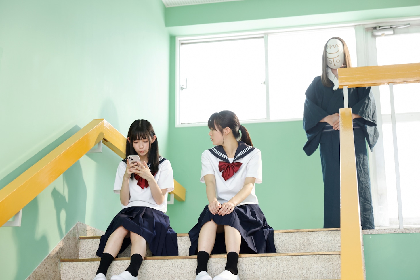 「とれ！」場面写真。地元の廃墟を訪れて以来、美咲は和装でお面のような顔の“神様”に憑きまとわれることになる